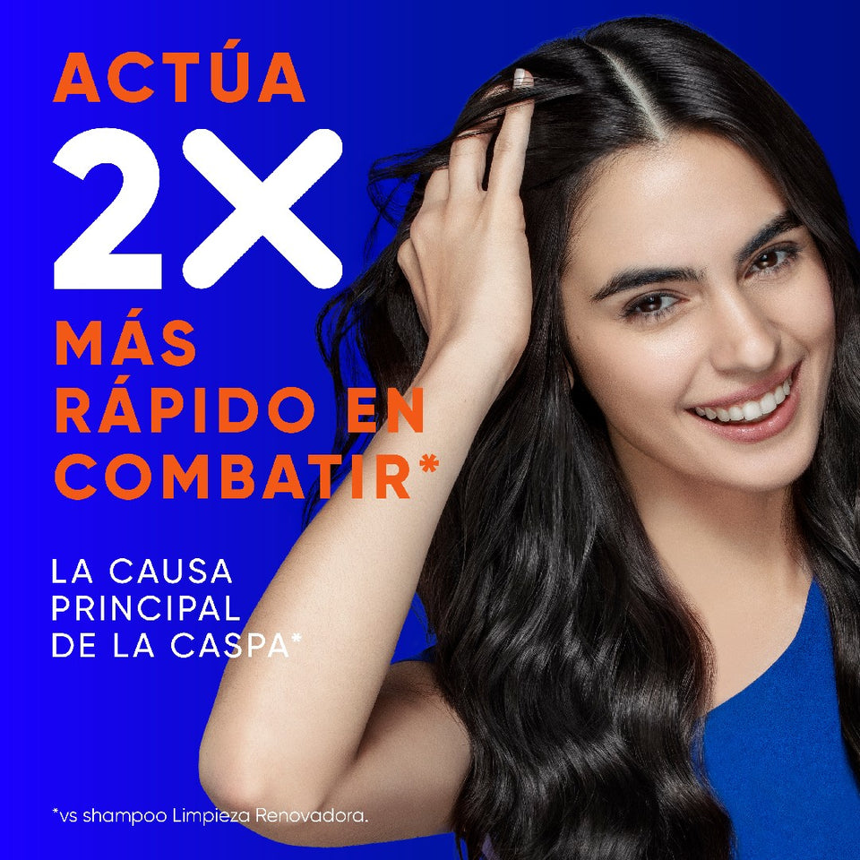 Mujer sonriente tocando su cabello sobre fondo azul, con texto "Actúa 2X Más Rápido en Combatir* la Causa Principal de la Caspa"